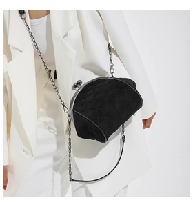 Detail of black quilted crossbody bag with matte finish and vintage metal clasp closure