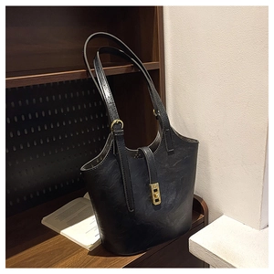 Detailed view of large black leather tote bag with golden buckle and adjustable straps