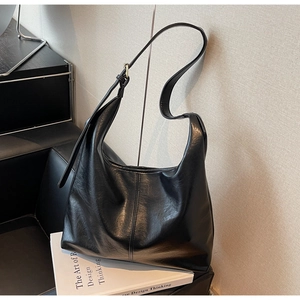 Close-up of black leather hobo bag with adjustable wide strap and gold hardware