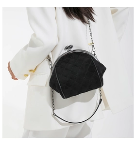 Detail of black quilted chain crossbody bag with metal frame and large ball clasp