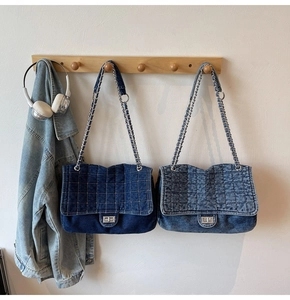 Détail de sacs matelassés en jean avec chaîne en bleu foncé et clair sur crochet mural