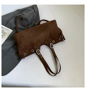 Detail of dark brown suede tote bag with metal eyelets and decorative buckles