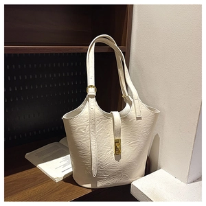 Detail of creamy white bucket bag with textured leather and golden metal clasp