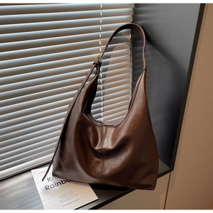 Detail of dark brown leather hobo bag featuring retro texture and adjustable bronze buckle