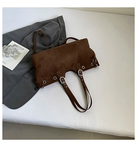 Detail of vintage brown suede tote bag with silver eyelets and adjustable straps