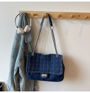 Détail d'un sac à main en jean bleu avec chaîne argentée et fermoir tournant en métal
