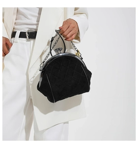 Close-up of black quilted crossbody bag with vintage metal clasp and chain strap detail