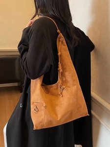Large brown suede tote bag with knotted shoulder strap shown in a stylish indoor setting