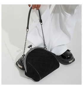 Detail of vintage black quilted suede frame bag with classic metal clasp and chain strap