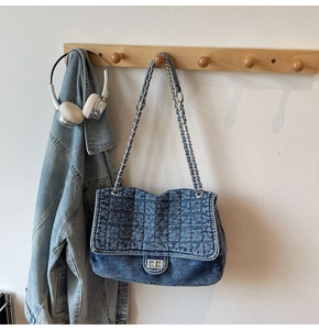 Détail d'un sac bandoulière en jean matelassé bleu avec fermoir rotatif argenté chic