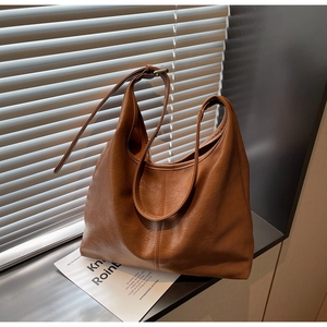 Detail view of brown leather tote bag with adjustable shoulder strap and soft texture