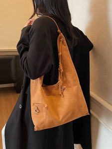 Large camel suede tote bag with knotted strap and metal ring detail shown on a model