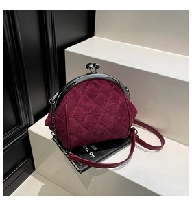 Detail of burgundy velvet quilted frame bag with silver clasp and metallic chain