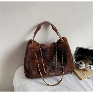 Close-up of brown faux fur tote bag featuring gold chain and sleek leather handle
