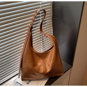 Close-up of caramel brown leather tote featuring vintage oil wax texture and copper buckle