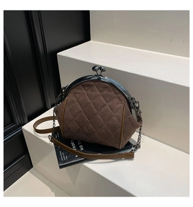 Detail of dark brown quilted suede clutch bag with metal clasp and chain strap