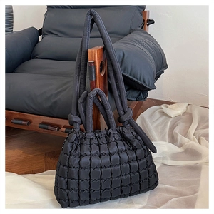 Détail d'un sac cabas noir matelassé avec des bretelles rembourrées sur une chaise