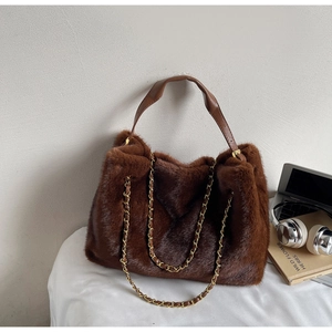 Detail of plush brown faux fur tote bag with leather handles and gold metal chain