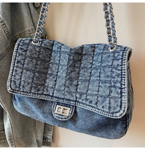 Détail du sac en denim matelassé avec bandoulière chaîne argentée et fermoir rotatif