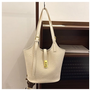 Detail view of the cream-colored bucket bag with a golden buckle and wrinkled leather texture