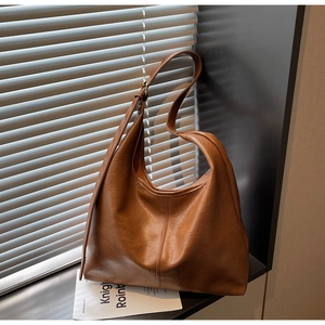 Detail of adjustable straps and textured brown leather on a hobo shoulder bag