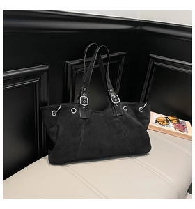 Detail view of black suede tote bag with silver eyelets and adjustable buckle strap