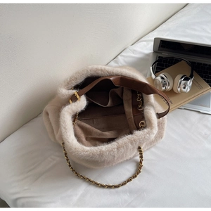Detail of plush off-white tote bag with brown leather handles and golden chain strap
