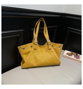Close-up of bright yellow suede tote bag with metallic silver eyelets and buckle details