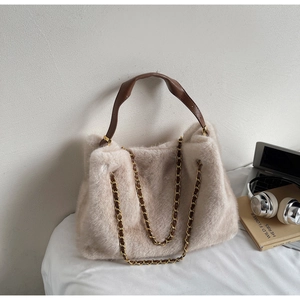 Detail of beige faux rabbit fur tote bag featuring brown leather straps and gold metal chains