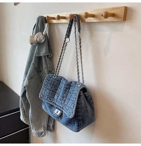 Détail du sac en jean matelassé avec bandoulière chaîne argentée et fermoir pivotant