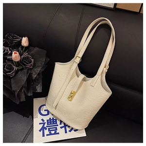 Detail of cream white bucket bag featuring pleated texture and golden metal lock clasp