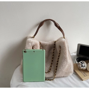 Detail of plush beige handbag with brown leather handle and gold chain shoulder strap