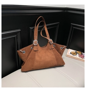Detail of vintage brown suede tote with silver eyelets and geometric winged design