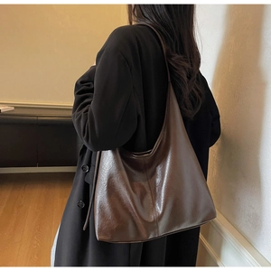 Detailed back view of a brown leather Hobo tote bag worn by a model in a black suit