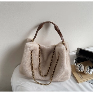 Detail of soft off-white faux fur tote bag with brown leather strap and gold chain