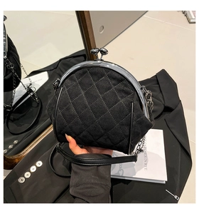 Close-up of black quilted suede kiss-lock bag with metallic chain strap and metal frame