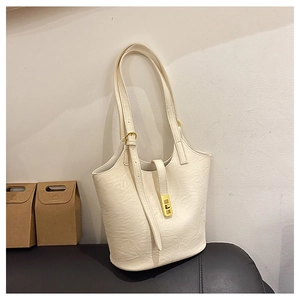 Close-up of cream white tote bag featuring golden metal clasp and wrinkled leather texture