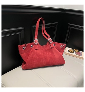 Detail view of red suede tote bag with silver rings and adjustable buckle strap