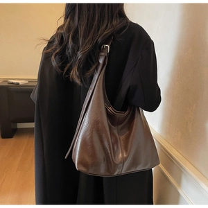 Large dark brown hobo tote bag shown on shoulder to highlight size and slouchy leather drape