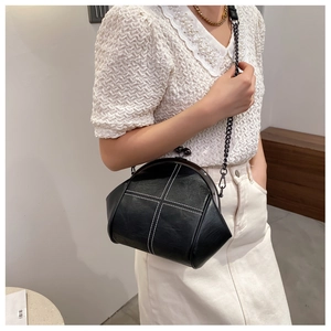 Detail of black shell bag with white cross-stitching and metal ball clasp closure