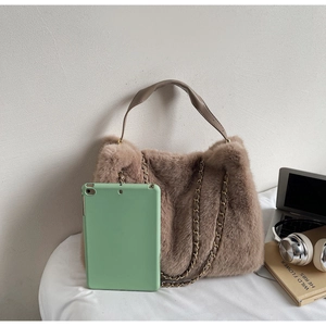Detail of plush brown faux fur handbag with gold chain strap and leather handle