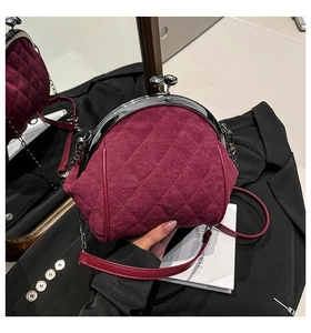 Detail of burgundy quilted suede handbag with vintage metal frame closure and chain strap