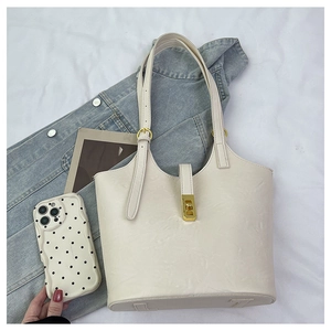 Detail of off-white tote bag with lychee grain texture and golden metal twist lock closure