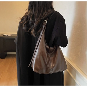 Detail view of large dark brown hobo shoulder bag with glossy leather and wide strap