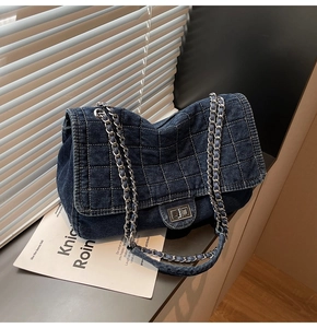 Détail du sac bandoulière en jean bleu avec surpiqûres et fermoir en métal argenté