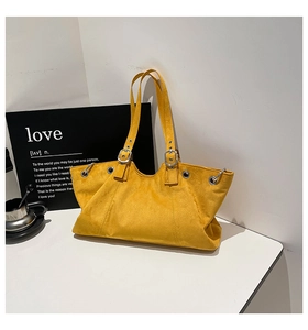 Close-up of bright yellow suede tote bag featuring silver grommets and metal buckle details