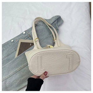 Detailed view of white textured faux leather tote bag with gold metal buckle and strap