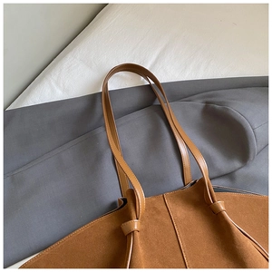 Detail of a minimalist brown suede tote bag featuring a stylish knotted shoulder strap