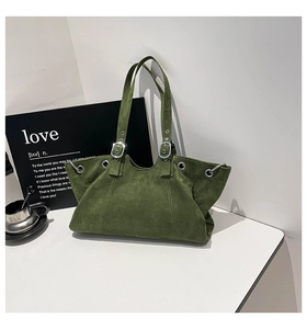 Detail view of dark green suede tote with silver metal buckles and retro grommet accents