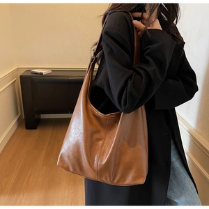 Detail of brown soft leather hobo bag with vintage lychee texture and wide strap